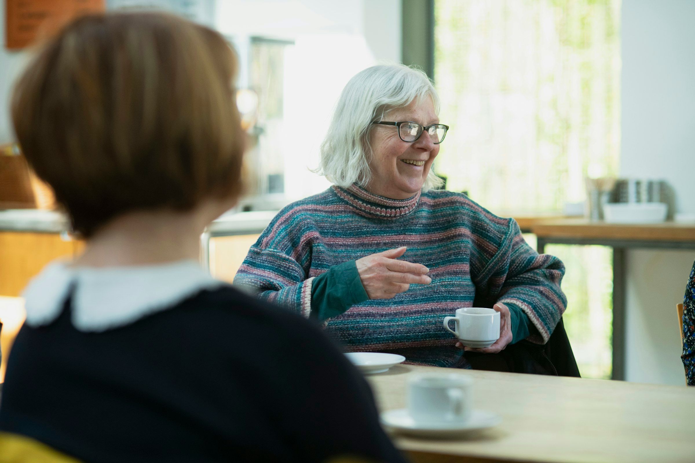 Eine Betreuungskraft und eine ältere Frau im Gespräch am Küchentisch